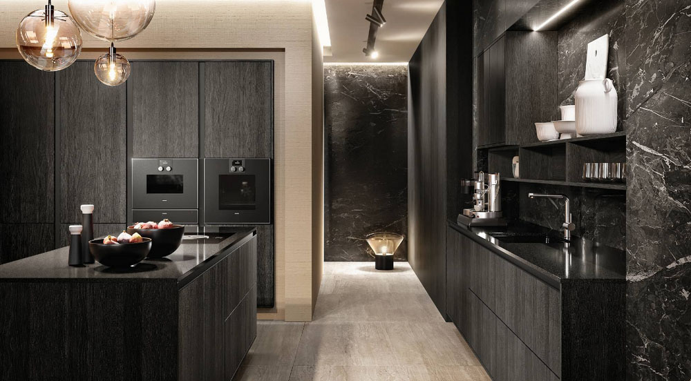 SieMatic Pure mat zwarte keuken met vrijstaand keukeneiland. De hoge keukenkasten hebben twee ingebouwde ovens. De werkbladen zijn glanzend zwart.